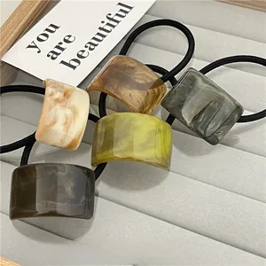 Detail view of five marble texture square hair ties in acetate on a velvet tray