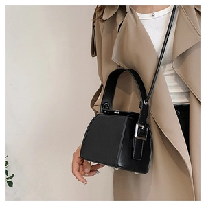 Detail showing a black PU leather box bag styled with a beige trench coat for a chic look