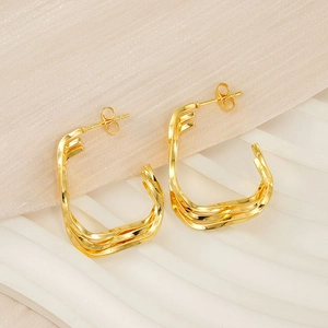Macro detail of golden multi-layer twisted geometric earrings with smooth metallic finish