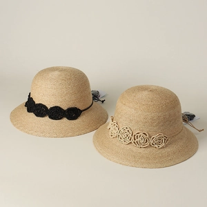Detail of raffia sun hats with elegant 3D woven flowers and wide brims for summer beach wear