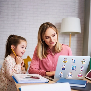 Waterproof cartoon cat stickers shown decorating a laptop lid in a warm home setting