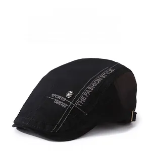 Detail of black beret cap featuring skull badge and white letter embroidery