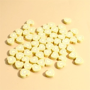 Macro shot of 10mm light yellow heart-shaped polymer clay beads with colorful swirl patterns