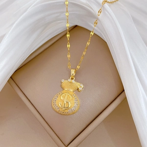 Close-up of golden money bag pendant with sparkling crystals on a beige jewelry box