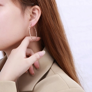 Detail of rose gold bamboo texture hoop earrings worn for a close-up side view