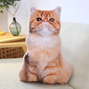 Realistic orange tabby cat plush pillow resting on a modern beige living room sofa