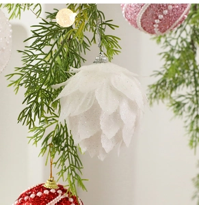 Close-up of white glitter leaf ornament and pearl foam balls on green pine branches