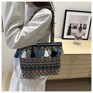 Detailed close-up of woven ethnic tote bag with stylish blue and white fringe accents