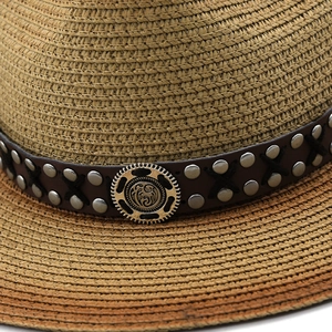 Close-up of a fedora straw hat featuring a leather band with metal studs and vintage gear buckle