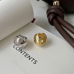 Detailed close-up of glossy gold and silver spherical stud earrings on a magazine