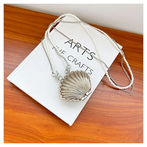 Detail of silver shell bag featuring pearl bead handle and metallic snake chain strap