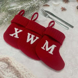 Close-up of red knitted Christmas mini socks with embroidered letters and pine decor