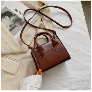 Detailed view of mini brown crossbody bag with handle on soft aesthetic background
