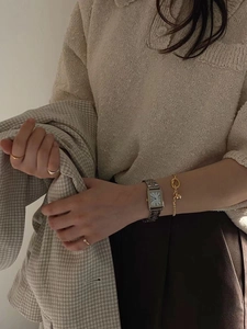Close-up of minimalist gold chain bracelet and silver square watch on model wrist