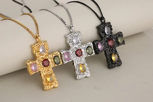 Close-up of gold, silver, and black cross necklaces with multicolored crystal zircon stones