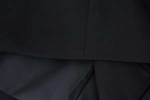 Close-up of the black woven fabric texture and stitching details on a stand collar dress