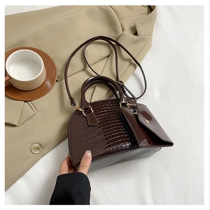 Macro view of dark brown crocodile-embossed shell bag with glossy leather finish