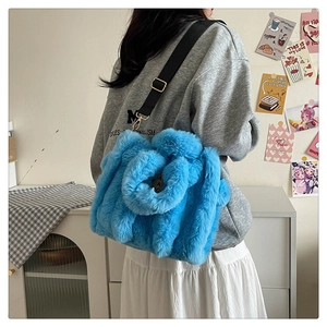 Detail of blue plush tote bag with adjustable black nylon strap and gold hardware
