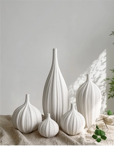 Dettaglio di vasi in ceramica bianca opaca con texture a coste su lino rustico