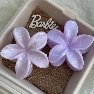Macro detail of two purple marble texture flower hair claws on a woven fabric base