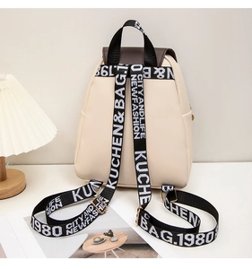Detail of minimalist school bag with cream body and black woven logo straps