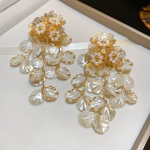 Detailed close-up of golden floral stud earrings with cascading white pearl petals