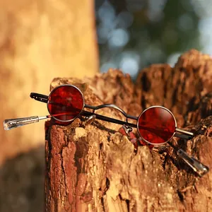 Retro steampunk round sunglasses with red lenses and dark metal frame on wood