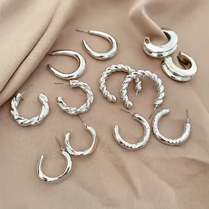 Set of six pairs of textured silver earrings with twisted and wave patterns on satin