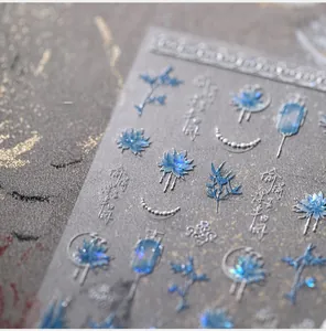 Macro detail of blue floral nail stickers with silver embossed lines and cloud patterns