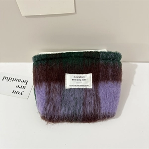 Detail of plush checkerboard pouch in dark green and purple with rectangular logo label