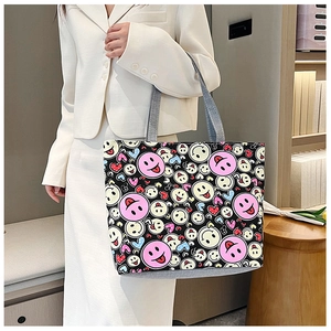 Detail of a casual black canvas tote bag with pink smiley face and colored hearts print