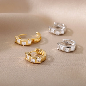 Detailed macro view of gold and silver geometric C-shape hoop earrings with zircon