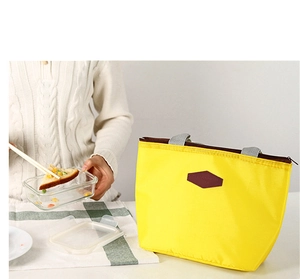 Close-up of bright yellow insulated lunch bag with gray handles and diamond leather patch