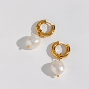 Gros plan sur les boucles d'oreilles en acier doré avec pendentifs perles baroques blanches