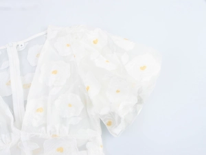 Close-up of white puff sleeves with 3D floral embroidery and lace texture on dress back