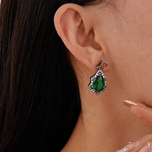 Close-up of vintage pear-shaped green zircon earrings with silver needle on ear