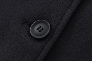 Détail macro du tissu noir en laine mélangée et finitions soignées des boutons