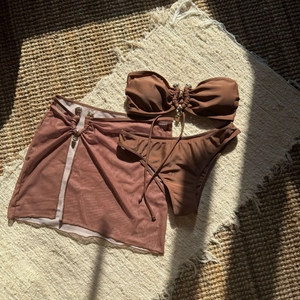 Détail de l'ensemble bikini 3 pièces marron chocolat avec jupe en résille et breloques
