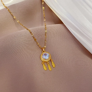 Close-up of golden dreamcatcher necklace with zircon feathers on soft silk background