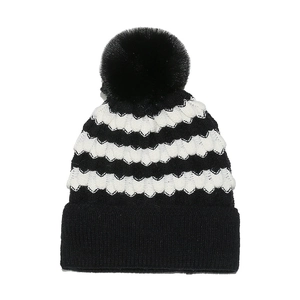 Women's black and white striped knit beanie with large faux fur pom pom decoration