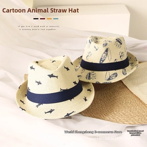 Detailed view of woven straw hat featuring cartoon shark and surfing prints with navy ribbon