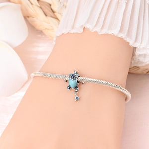 Bracelet maille serpent argenté avec breloques tortue bleue et étoile sur fond doux