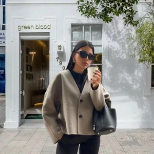 Women's beige double-breasted knit cardigan jacket styled with a black leather bucket bag