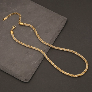 Detail of two-tone gold and silver twisted cable chain necklace on textured stone plate