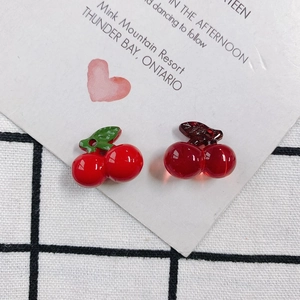DIY red acrylic cherry pendants set on a black and white checkered fabric background