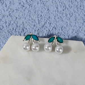 Detailed view of cherry stud earrings with white pearl fruits and green enamel leaves