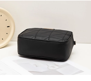 Close-up of black quilted PU leather crossbody bag featuring gold zipper and D-ring detail