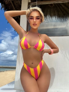Detail eines gestreiften Bikinis in Rosa und Gelb vor sonnigem Strandhintergrund