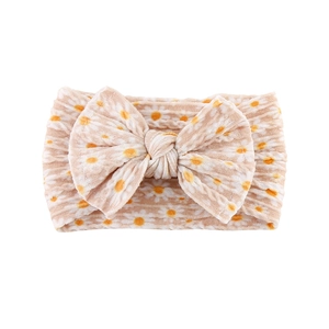 Close-up of beige baby headband with white daisy print and soft ribbed knit texture