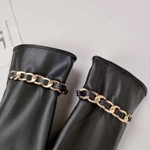 Close-up of black PU leather gloves with decorative golden chains on wrist detail